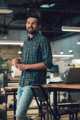 Cheerful man relaxing with tasty tea during free time at work