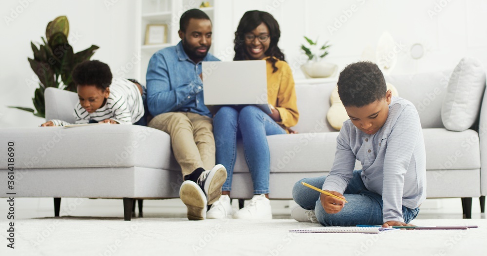 Happy african american family sitting on sofa together with device at ...