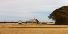 Panoramic Image Of An Old Timber Worn Out Abandoned Traditional Australian Farm House In The Middle Of A Newly Harvested Field On A Agricultural Property In Rural Victoria, Australia