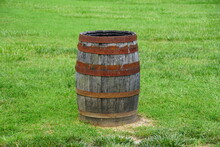 A Brown Barrel With Rusty Metal On The Top Of Green Grass