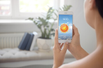 Wall Mural - woman using weather forecast app on smartphone indoors, closeup. space for text
