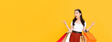 Attractive Beautiful Asian Woman With Colorful Shopping Bags Pointing To Empty Space Isolated On Colorful Yellow Banner Background