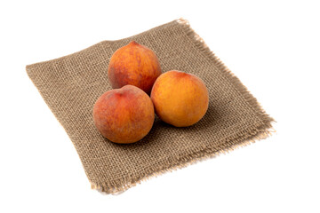 Peaches. Three peaches on burlap isolated on a white background.