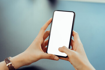 Closeup of young woman hand holding smartphone on the table and the screen is blank, social network concept..