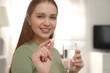 © New Africa - Woman with glass of water and vitamin pill indoors, focus on hand