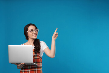 Poster - Young woman with laptop on blue background. Space for text