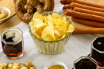 Wall Mural - Glass bowl of potato crisps with beer on a wooden table