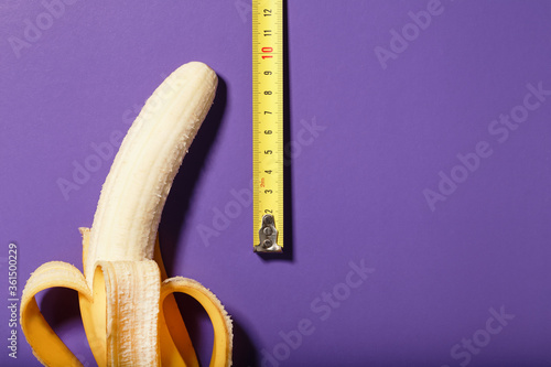 Fotografía Yellow banana penis concept measured by measuring tape on a purple background