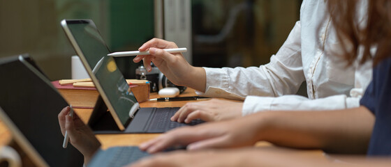 two female workers consulting on their project while working with mock-up tablet on wooden table