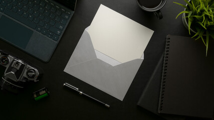 Wall Mural - Open mock-up invitation card with grey envelope on dark modern office desk with office supplies