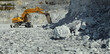 © esalienko - Excavator with hydraulic hammer crushes large stones in a limestone quarry, panorama.