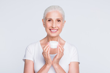 Sticker - Portrait of lovely grandmother holding jar with nourishing procedure looking at camera wearing stylish trendy t-shirt isolated over white background