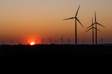 Black Silhouette of windturbines energy generator on amazing sunset at a wind farm in germany