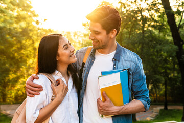 Wall Mural - Image of cheerful multicultural student couple hugging and smiling
