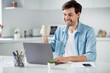 © deagreez - Photo of handsome guy young student browsing notebook sitting table video call teacher work house online lesson conference friendly talk drink tea good mood social distance quarantine indoors