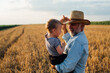 © cherryandbees - man holding his grandson standing in wheat field