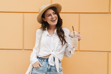 Sticker - Portrait of happy woman drinking milkshake and smiling while walking