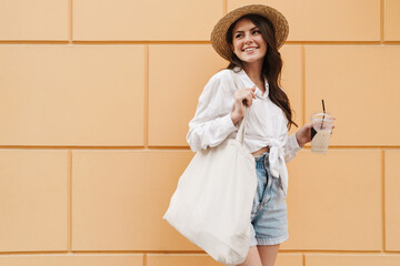 Sticker - Portrait of happy woman drinking milkshake and smiling while walking