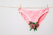 © Georgii - Pink women's underwear decorated with flowers on clothesline isolated on white, concept photography for feminist blog