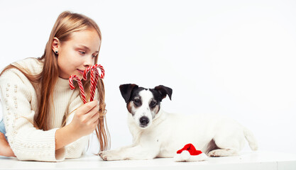 pretty young blond girl with her little cute dog wearing Santas red hat at Christmas holiday isolated on white background, lifestyle people concept