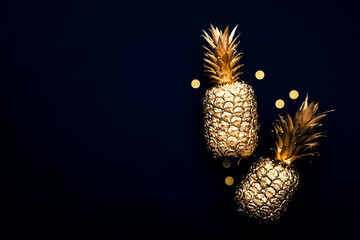 Flat lay tropical gold pineapple and confetti on a dark background