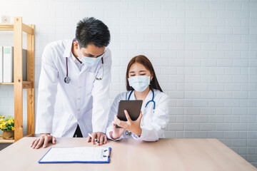 Asian Medical healthcare doctor colleague teamwork working together examine diagnosing discussing using tablet wearing surgical mask work at home modern office wireless online technology communication