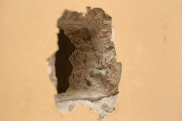 A hole cut in a yellow concrete wall for installing the elevator button Left view