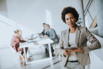 Young African American businesswoman standing using digital tablet in a modern office