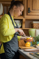 Wall Mural - beautiful young girl in black apron cooks in kitchen of cozy wooden country house. Rustic style. healthy eating concept.