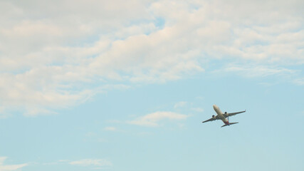 Passenger airplane takes off against the blue sky with clouds.