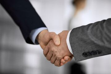 Business people in office suits standing and shaking hands, close-up. Business communication concept. Handshake and marketing