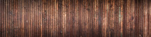 Wide Striped Panoramic Background Of Vertical Dilapidated Narrow Wooden Boards With Old Brown Paint And Varnish
