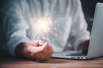 Aufkleber - hand of a man with a light bulb with network connection line And he is using a notebook computer. The idea of ​​inspiration from online technology.innovation idea concept.