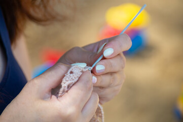 Hands of a woman who knits with an aluminum crochet