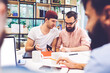 © BullRun - Portrait of young male colleagues streaming video in social network while discussing usability of modern devices sitting at the table in coworking office using smartphone and fast 4G connection