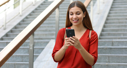 Wall Mural - Portrait of beautiful woman walking down the stairs holding her phone