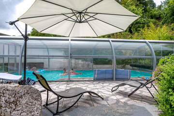 Swimming pool with a roof with kids playi,g inside oin a garden