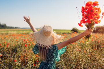 Wall Mural - Young woman raised arms holding bouquet of poppies flowers walking in summer field. Happy girl feeling free