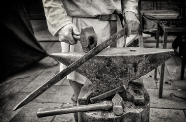 craftsman forging a sword with a hammer blow black and white 