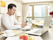 © imtmphoto - young asian businessman working from home checking message using cellphone