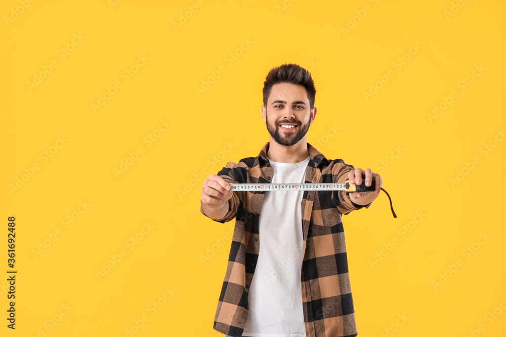 Young man with measuring tape on color background