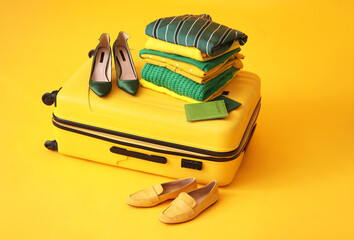 Suitcase with travel accessories on color background