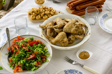 Wall Mural - Dinner table with fried chicken wings, tomato salad and snacks