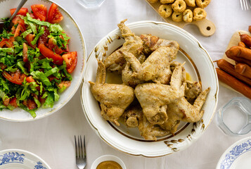 Wall Mural - Dinner table with fried chicken wings, tomato salad and snacks