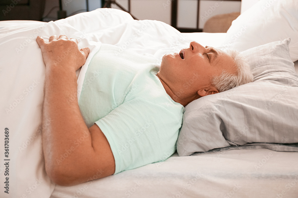 Mature man snoring while sleeping in bed. Apnea problem