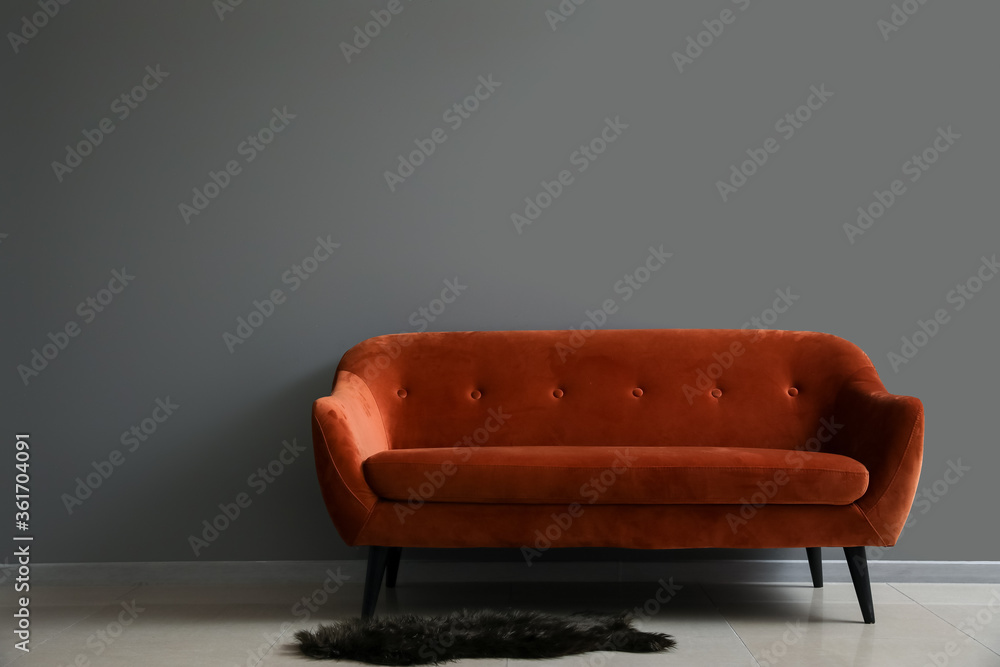 Stylish sofa near grey wall in room