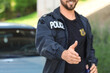 © Pixel-Shot - Handsome male police officer giving hand for handshake outdoors