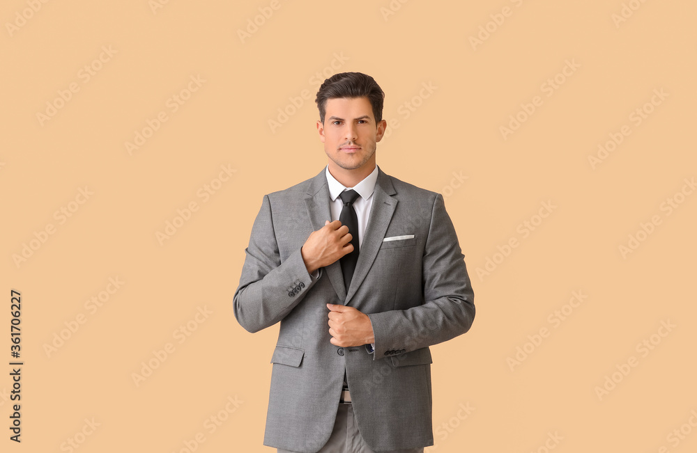 Young businessman in stylish suit on color background