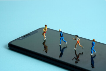 Running and jogging tracking app concept. A family running above smartphone. Miniature people figure photography.