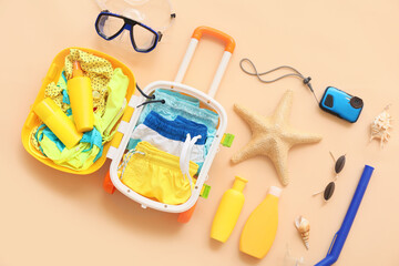 Suitcase with beach accessories on color background